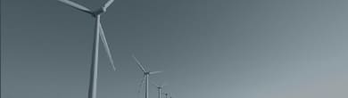 An image of wind power generators lined up over the sea.