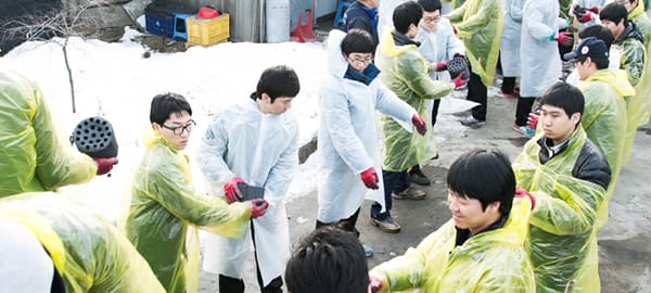 People in raincoats are engaged in volunteer work, carrying briquettes.