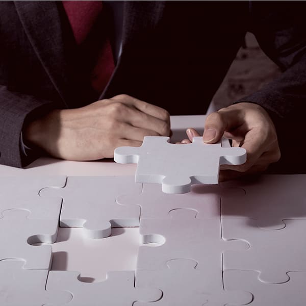 An image of a person holding the last piece of a puzzle on a desk.